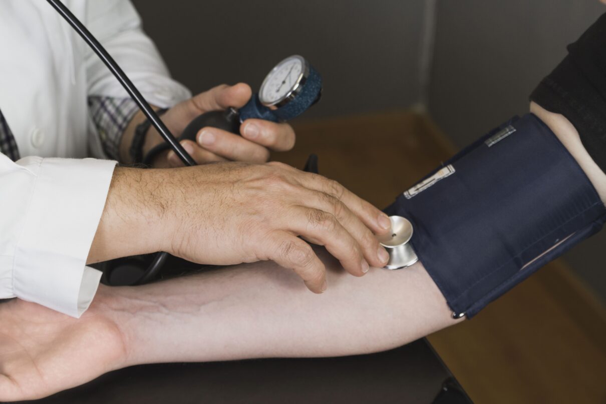 Doctor performing physical exam using stethoscope to check patient's heartbeat