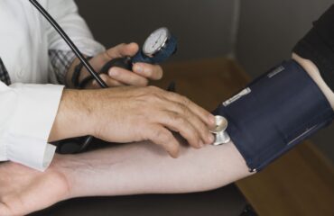 Doctor performing physical exam using stethoscope to check patient's heartbeat