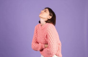 young woman wearing pink sweater having a Women’s UTI & Allergy and she isolated purple wall