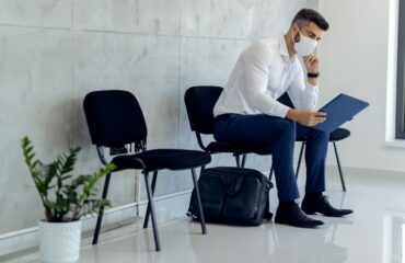 businessman wearing protective face mask while waiting pre-employment physical exam