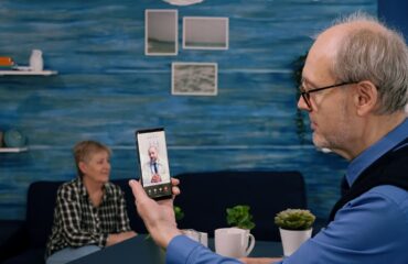 retired male holding smartphone onlinecconsultation listening young physician doctor sitting living room providing telehealth diabetes care